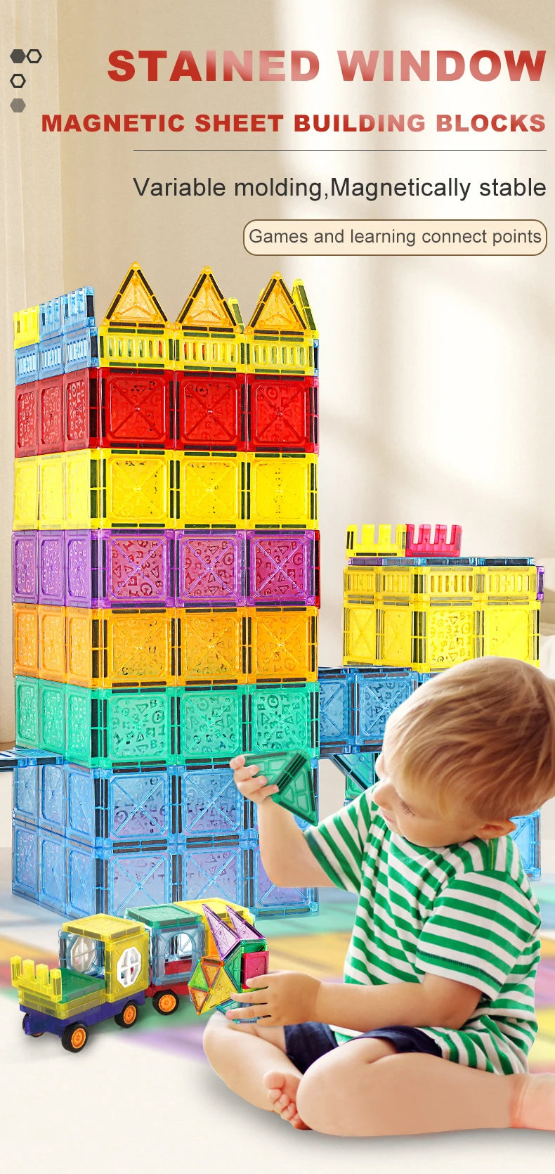 A young child is building a tower with colorful magnetic sheet building blocks on a light-colored surface.