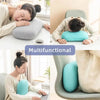 A woman rests her head on a light blue memory foam travel neck pillow while working at a desk.