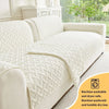 A white quilted anti-slip sofa cushion lying on a light gray sofa.
