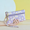 A hand holds a purple daisy print PU leather wristlet wallet with a zipper closure against a yellow background.