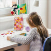 A young girl is looking at a wooden star reward jar on a desk.