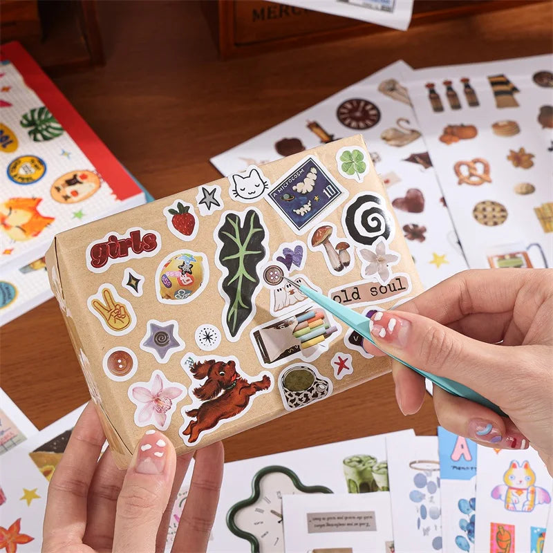 A box of aesthetic nature stickers featuring various designs like leaves, fruits, and animals for scrapbooking