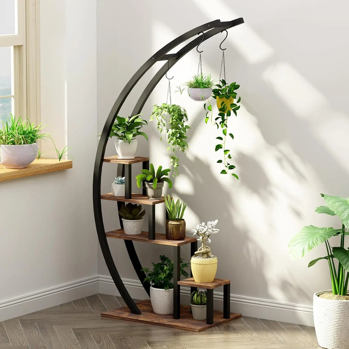 A black metal half moon stand with five tiers holds potted plants and features hanging hooks.