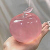 A hand holds a translucent pink fruit-shaped squeeze toy with a clear dropper top for stress relief.