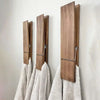 A set of rustic wooden wall-mounted towel clips with metal hooks displayed against a white wall.