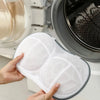 Hands hold a white mesh laundry bag with anti-deformation protection inside a washing machine drum.