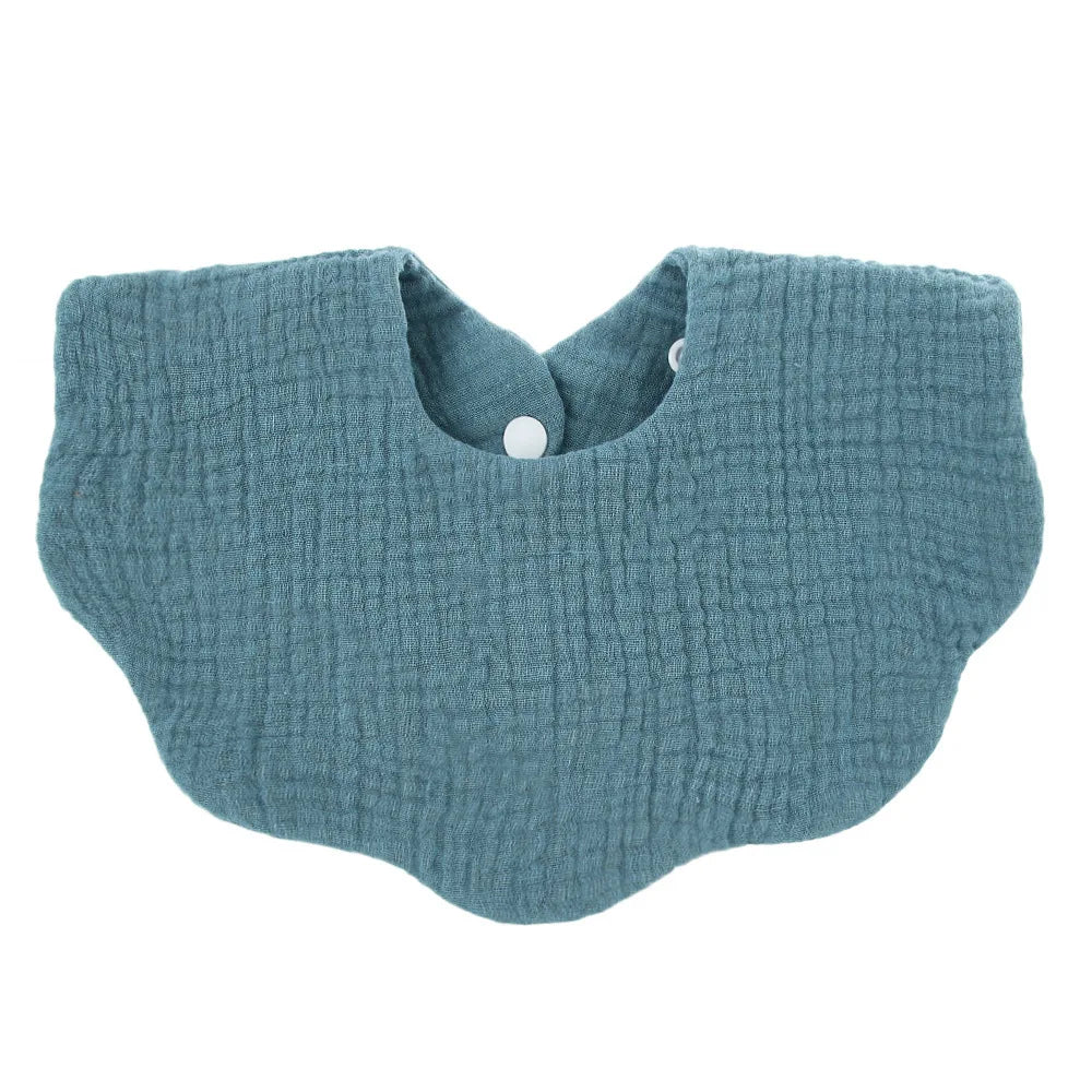 A soft teal knitted baby bib in a bandana style with a cutout for the baby's neck.