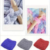 A collection of extra thick chenille yarn in various colors including purple, gray, and pink, shown in a close-up view.