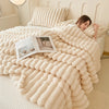 A fluffy cream flannel blanket is draped over a bed, with a person resting under it.