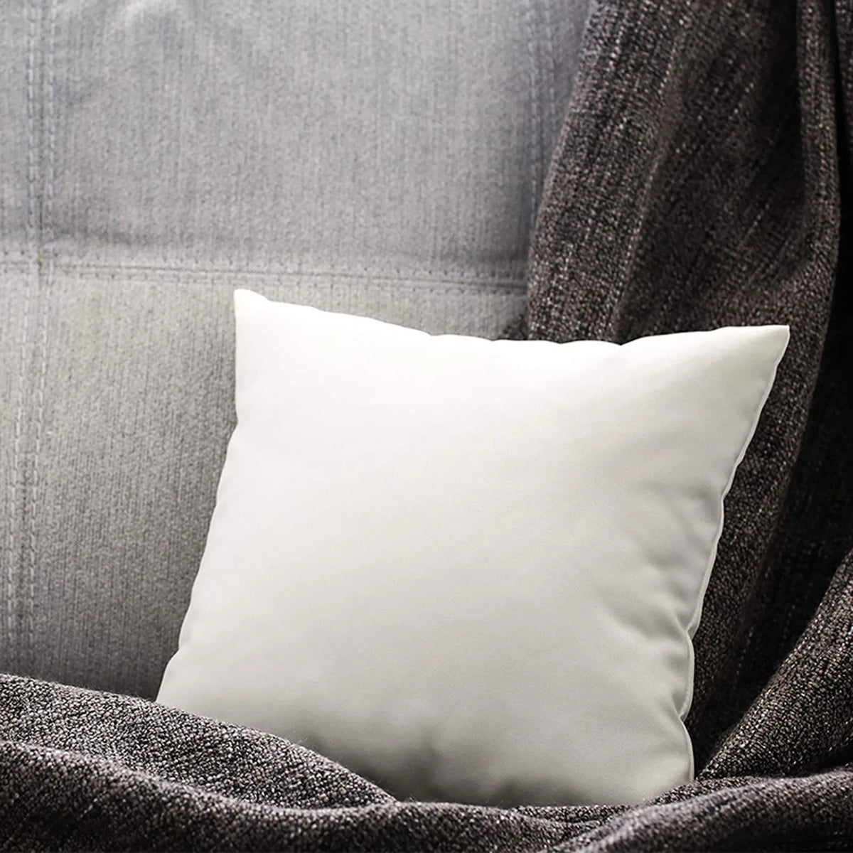 A white soft comfort cushion resting on a dark gray textured fabric.