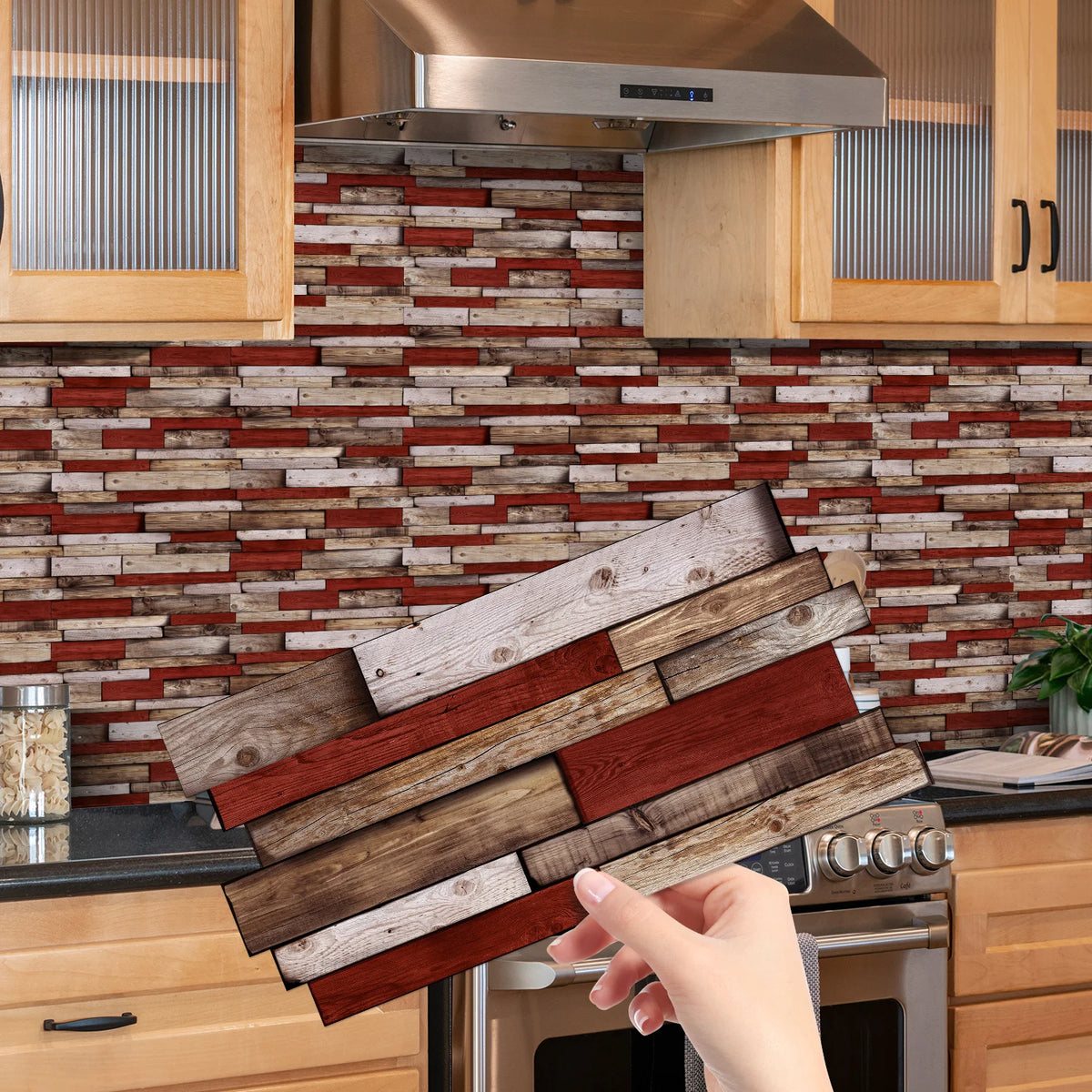 A hand holds a wooden tile sticker piece against a rustic brick backsplash in a kitchen setting.