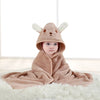 A baby wearing a brown fuzzy hooded bathrobe with cartoon animal ears lying on a white rug.