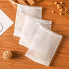 Three clear mesh soap net bags are displayed on a wooden surface next to a small ball of natural fiber.