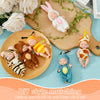A set of six mini reborn baby dolls with various outfits arranged on a wooden cutting board and plate.