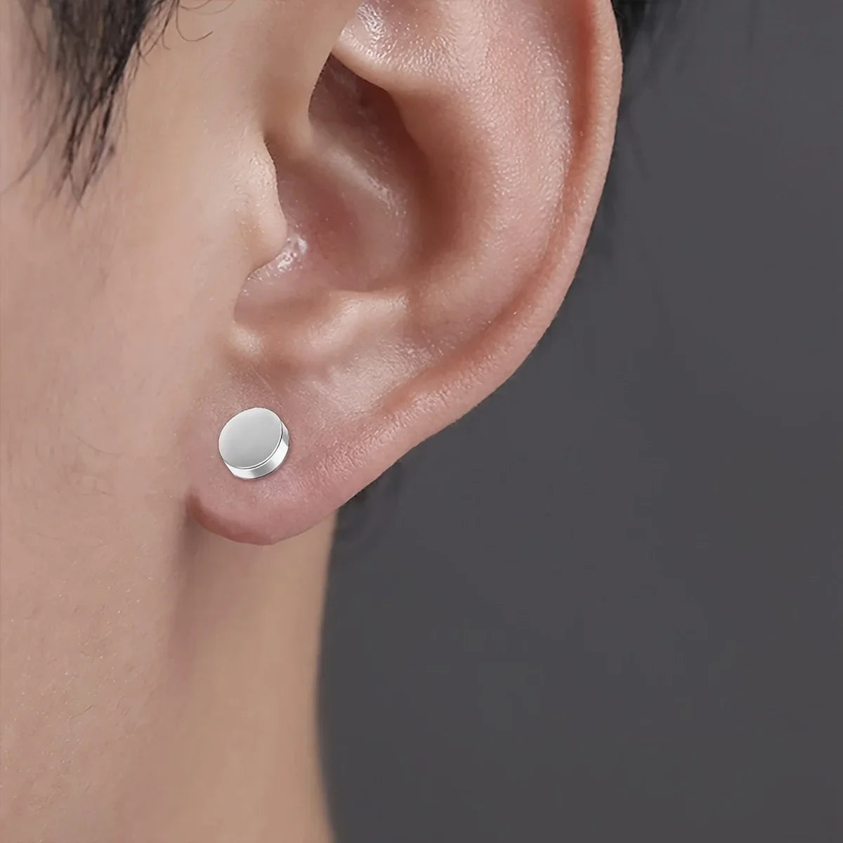 Boucles d'oreilles à clips magnétiques rondes en cristal argenté, montrées sur une oreille humaine.
