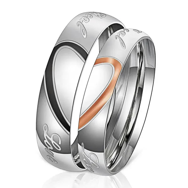 A pair of silver stainless steel promise rings featuring a heart design and the word love engraved on them.