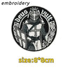 Black and white embroidery design featuring a stylized archangel figure with a helmet and sword.