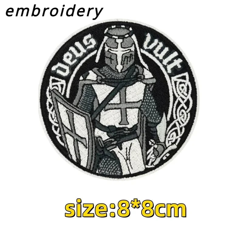 Black and white embroidery design featuring a stylized archangel figure with a helmet and sword.