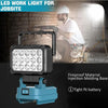 A portable LED work light mounted on a molding base, shown illuminating a construction site.