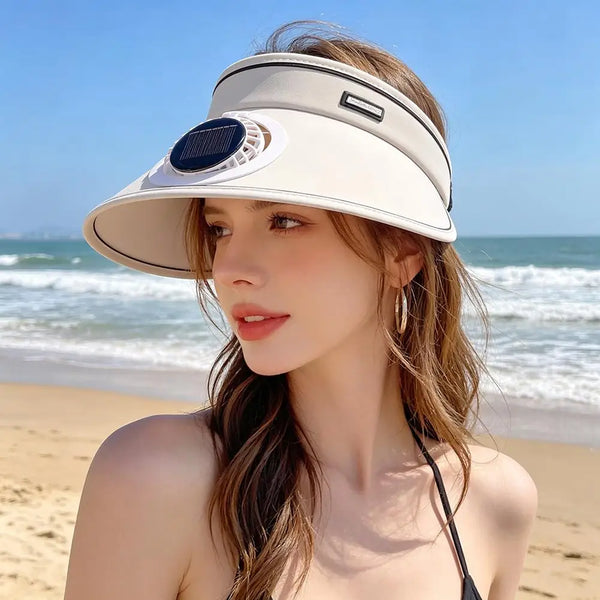 A woman wearing a beige solar-powered cooling sun hat with an adjustable fan on a beach.