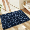 A dark blue plush non-slip bathroom rug with a pebble texture placed on a light wooden floor.