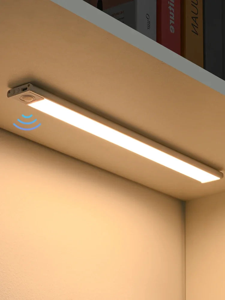 A long, rectangular LED light fixture with a motion sensor is mounted on a wall in a room.
