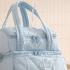 A light blue insulated lunch bag is shown with water dripping onto the fabric.