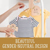A yellow baby shirt is hanging on a wooden hanger next to pink and natural wood closet dividers.