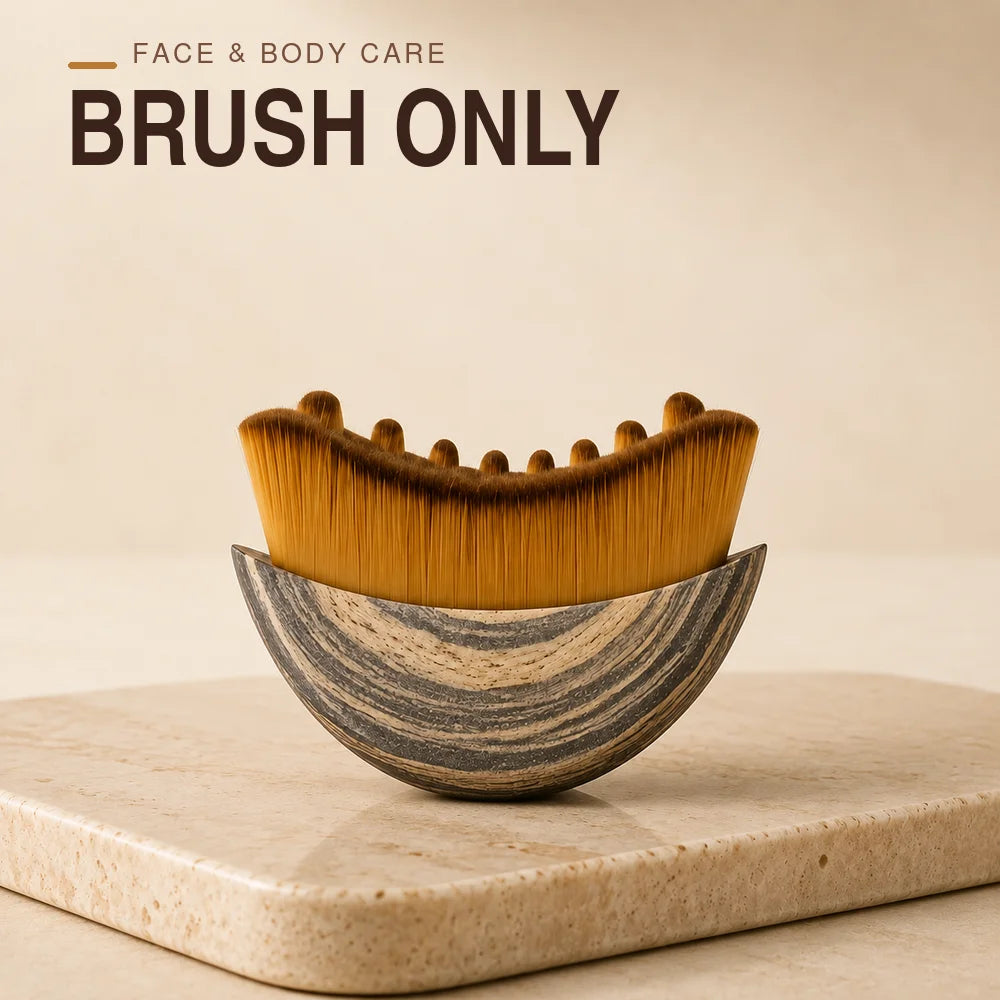 A wooden facial brush with golden bristles rests on a light stone surface.