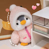 A pink penguin plush toy with a white hat is displayed next to a white storage box.
