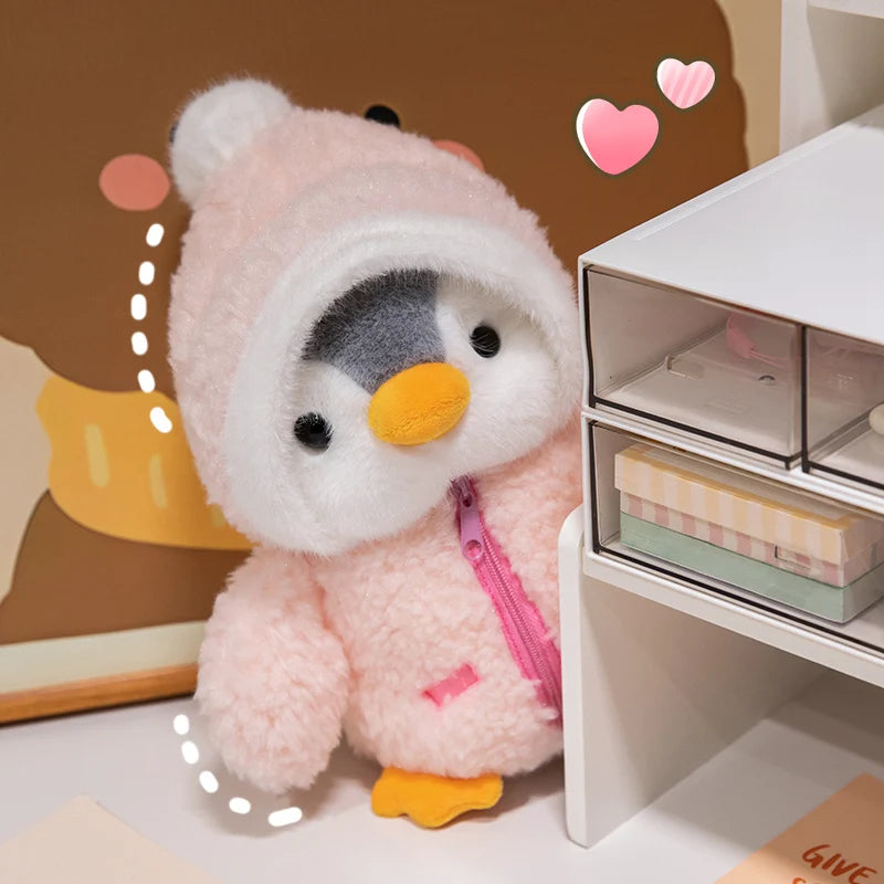 A pink penguin plush toy with a white hat is displayed next to a white storage box.