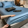 Un juego de sábanas ajustadas de algodón de lujo azul claro está tendido sobre una cama, con una mano ajustando la tela.