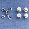 A collection of silver metal jeans button snaps and clips on a blue denim background.