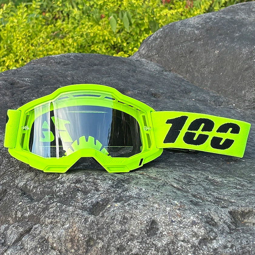 A pair of neon yellow motocross goggles with a black lens resting on a dark rock.