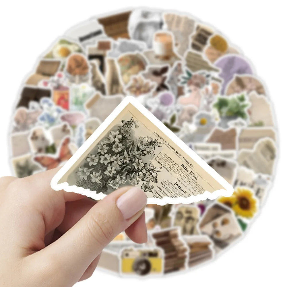 Une main tient un paquet d'autocollants vintage avec des éléments botaniques et rustiques pour journaux et carnets de souveni