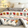 A cozy, multi-patterned plush throw blanket featuring floral designs in orange, red, and blue on a white background.