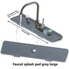 A large grey silicone faucet splash pad with a spout and drain is shown on a kitchen sink.