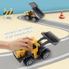 A yellow die-cast construction truck toy excavator is shown driving on a gray track with a hand interacting with the vehicle.