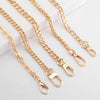 Several gold-colored metal purse chains with adjustable buckles laid out on a white surface.