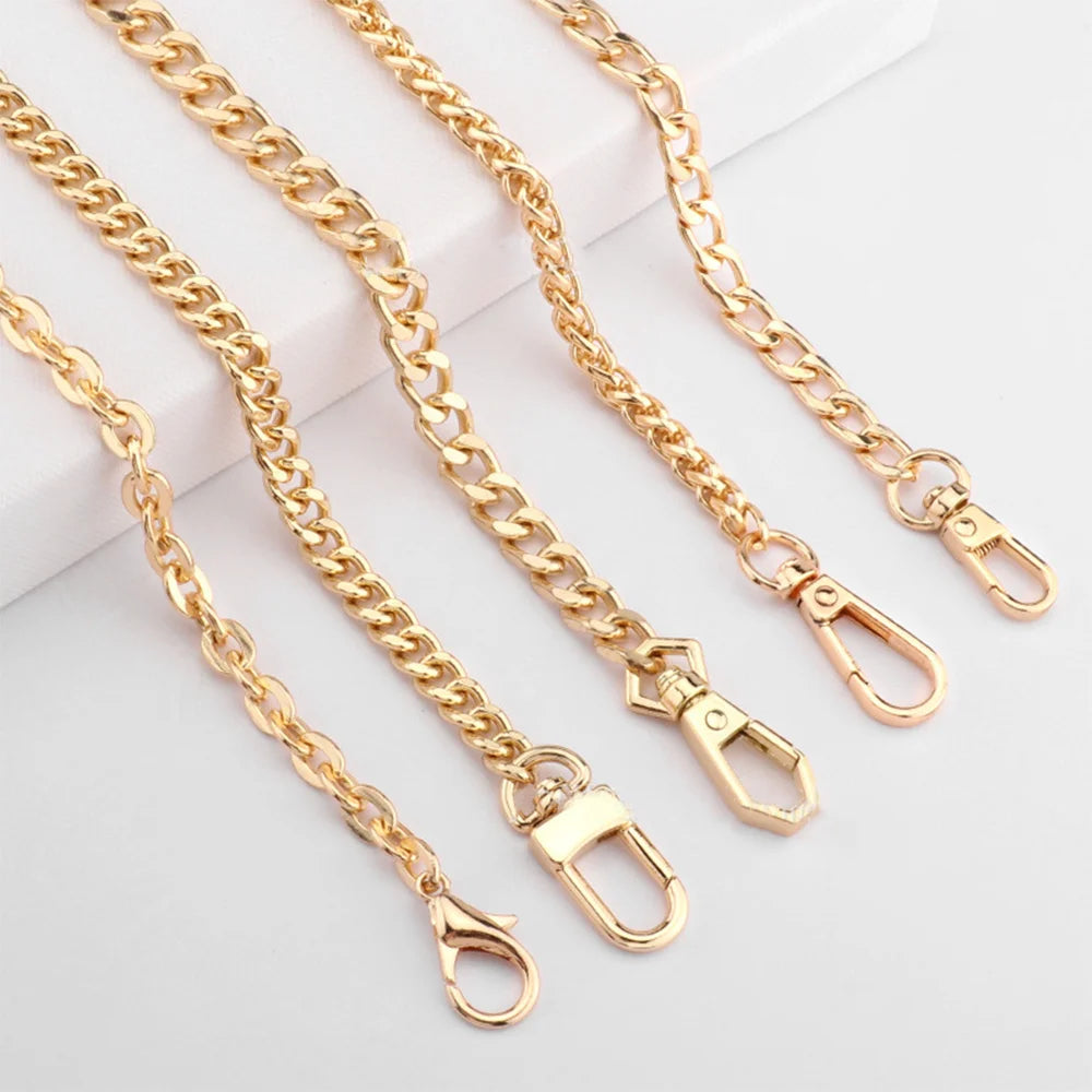 Several gold-colored metal purse chains with adjustable buckles laid out on a white surface.