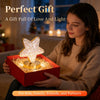 A person holds a red gift box containing a glowing crystal star night light for a perfect gift.