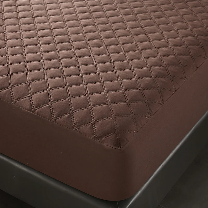 A close-up view of a brown quilted mattress protector with a deep pocket design.