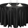 A black satin tablecloth set for a round table with wine glasses and napkins.