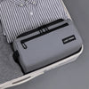 A gray toiletry bag with a black carry handle is shown inside a light-colored case, next to a striped shirt.