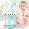 A baby is holding a pink and teal musical rabbit rattle teether toy.