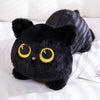 A black plush cat toy with large yellow eyes lying on a white surface.