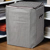 A large checkered fabric storage bag with handles is placed on a shelf among folded textiles.