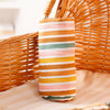A striped orange and pastel muslin baby swaddle blanket is displayed next to a woven basket.