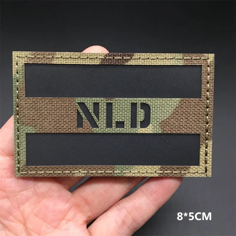 A rectangular tactical patch featuring a camouflage pattern with the letters N.L.D. displayed in white text.