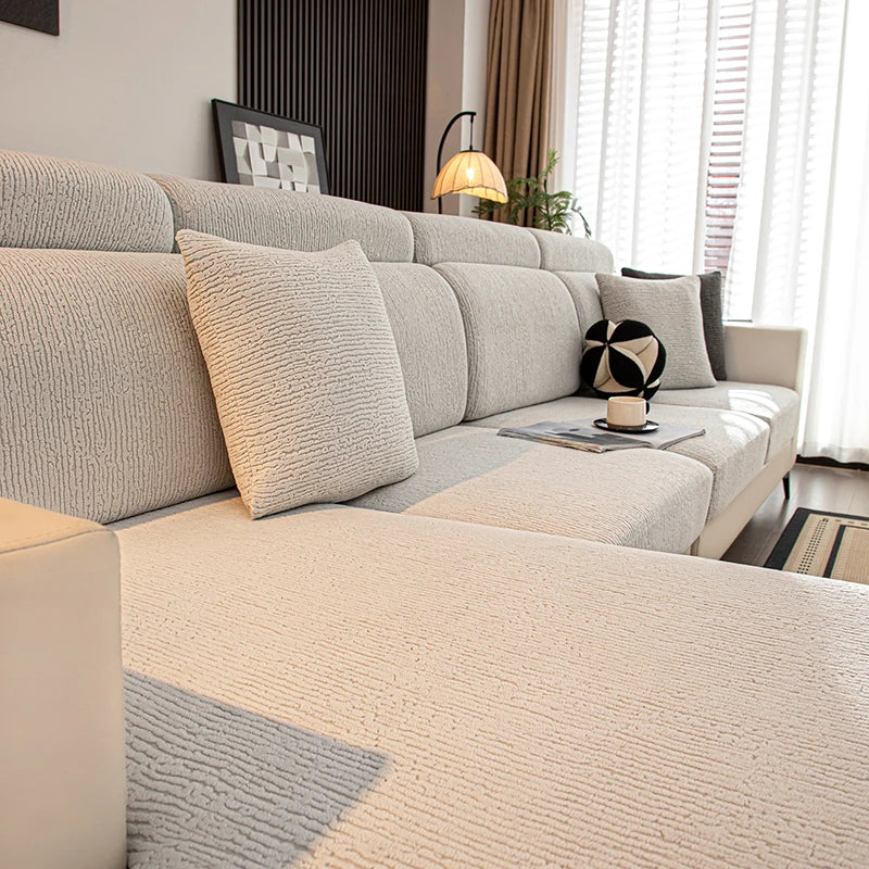 Funda de cojín de asiento beige claro y elástico para un sofá modular moderno con decoración neutra.